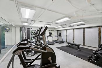 A gym with treadmills, elliptical machines, and a bench press.